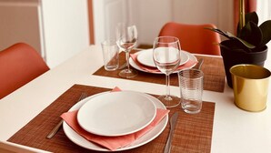 A dining table set with plates, glasses, and cutlery, a potted plant, and a gold-colored container.