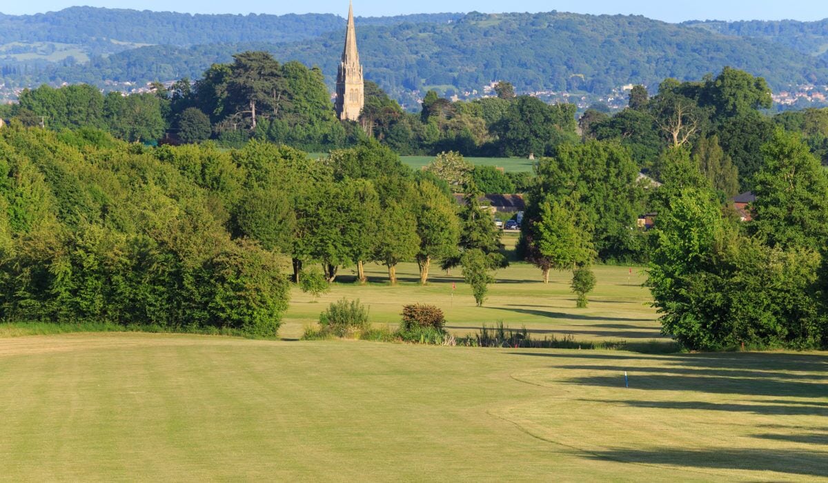 A golf course with a church spire in the background.