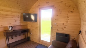 Tunnelmallinen mökin sisustus, jossa on puupanelointi, sohva, televisio ja lämmitin.