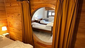 Una habitación de cabaña de madera con una cama, una mesita de noche y una ventana.