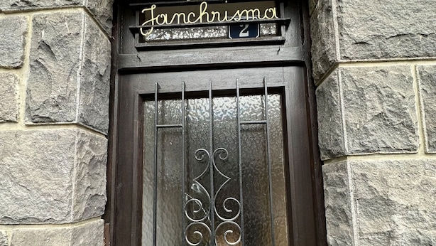 Un edificio de piedra con una puerta de madera oscura, una reja metálica y un letrero que dice 