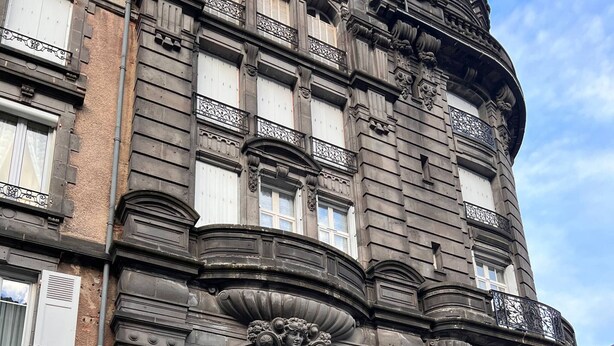 Un bâtiment historique doté de détails architecturaux raffinés, notamment une grande porte noire et des balcons décoratifs.
