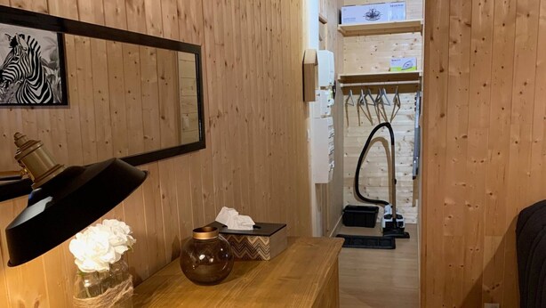 Un interior de madera con un escritorio, una lámpara, frascos decorativos y un espejo.