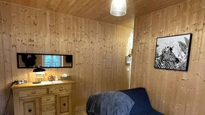 Habitación con paneles de madera, una cama, un aparador y una lámpara colgante.