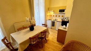 Une cuisine compacte avec un coin repas, comprenant une table avec des chaises, un petit réfrigérateur, un four à micro-ondes et un évier.