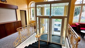 Un hall d’hôtel avec un grand escalier, une horloge et une vue sur l’extérieur.