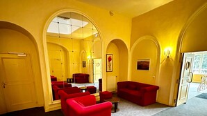 Une pièce avec des canapés rouges, une table ronde et un grand miroir.