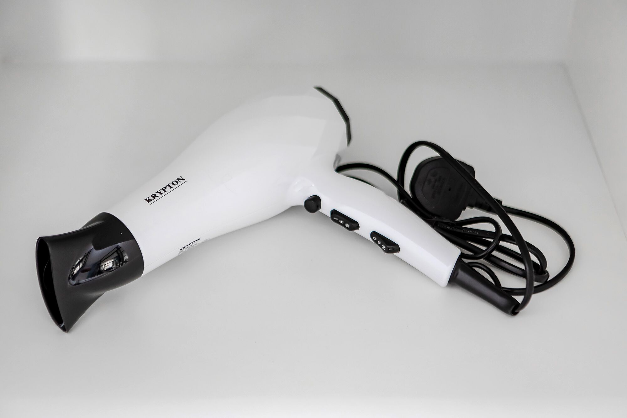 Een witte haardroger met een zwarte kabel en een stroomadapter.