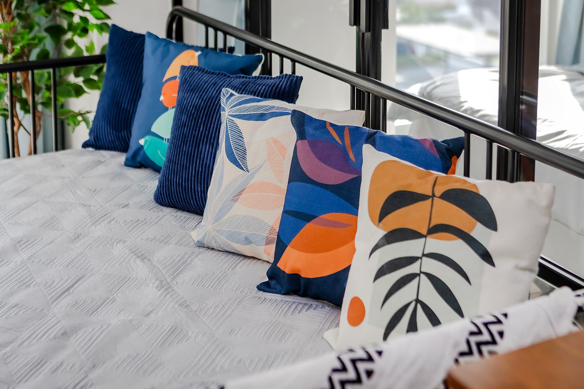 A bed with a patterned bedspread and several pillows with abstract designs.