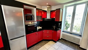 A compact kitchen with red cabinets, a stainless steel refrigerator, a Bosch oven, and a microwave. - Le Rocher - Le Mont Dore 6 pers (Mont-Dore)