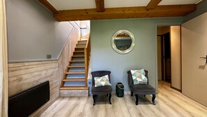 A staircase leading to a loft bedroom with a wooden ceiling, a small round mirror, two armchairs with patterned cushions, and a wooden floor. - Le Rocher - Le Mont Dore 6 pers (Mont-Dore)
