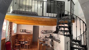 Un vaste loft comprenant une cuisine, un coin repas et un escalier en colimaçon noir.