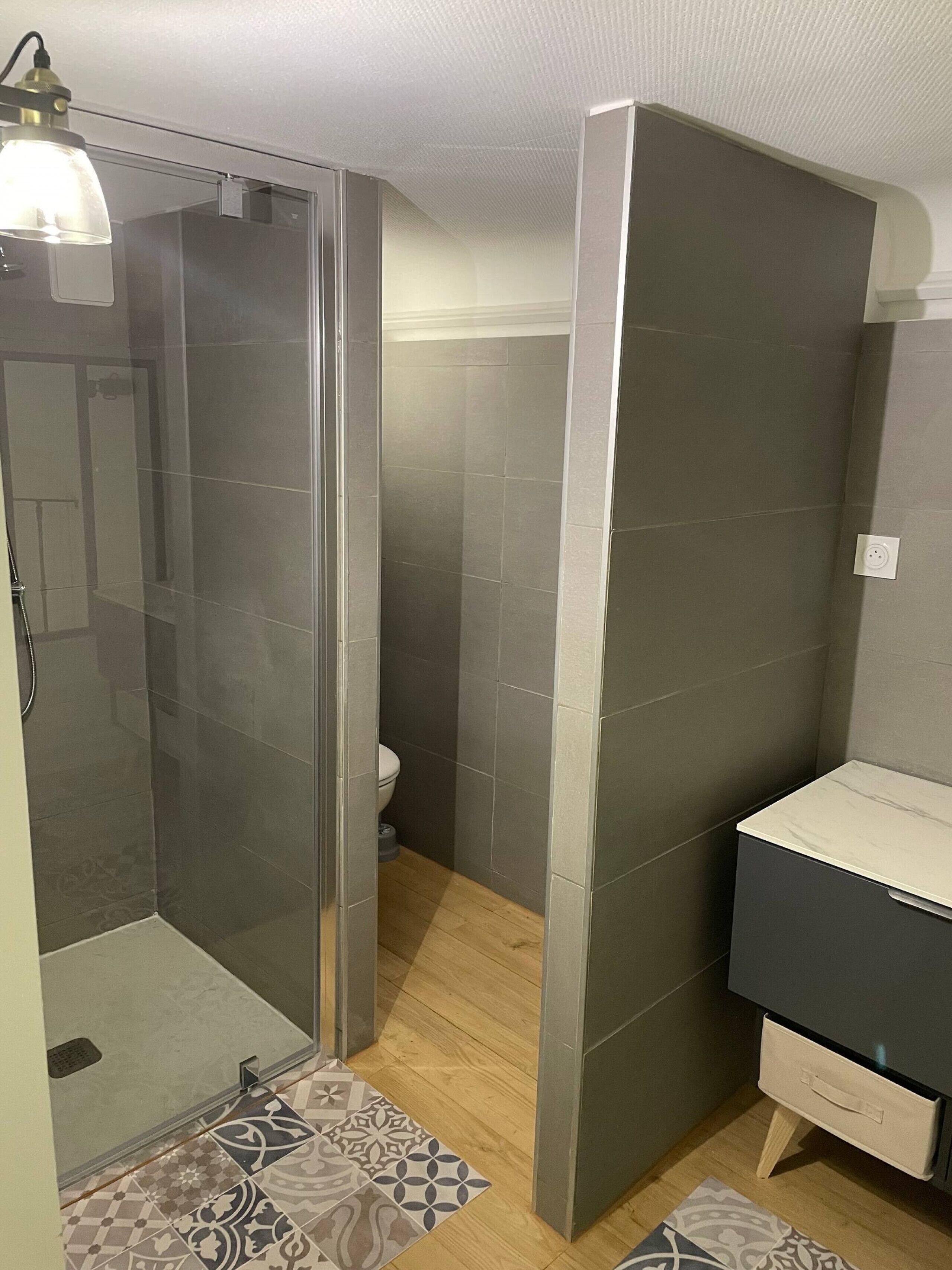 Ein modernes Badezimmer mit Duschkabine aus Glas, Toilette und Waschtisch mit Spiegel.