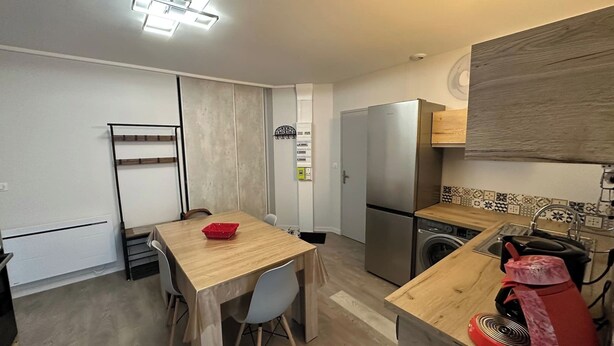 A compact kitchen with a wooden table, chairs, a refrigerator, a washing machine, and a sink. - Ruche 5 - Le Mont Dore 7 pers (Mont-Dore)