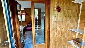 Un intérieur en bois avec une porte vitrée donnant sur un balcon, une moquette bleue et une étagère avec un panier.