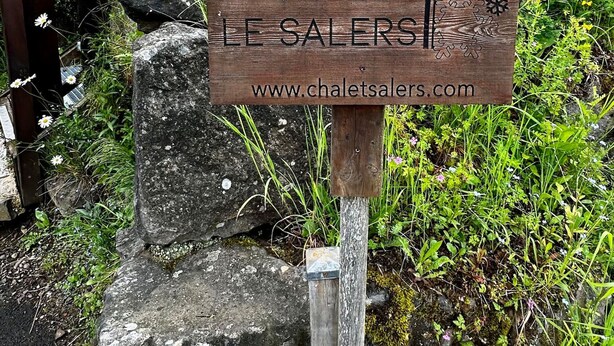 Une enseigne en bois portant l’inscription « CHALET LES SALERS » et l’adresse d’un site web.
