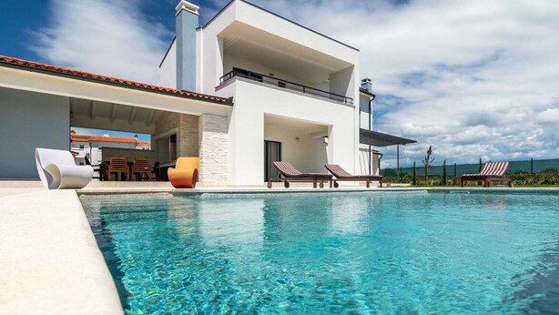 A modern two-story house with a swimming pool, lounge chairs, and a patio area. - Villa Jan in Valbandon (Valbandon)