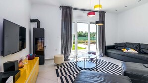A modern living room with a flat-screen TV, a fireplace, a sofa, and a dining area with a yellow cabinet. - Villa Jan in Valbandon (Valbandon)