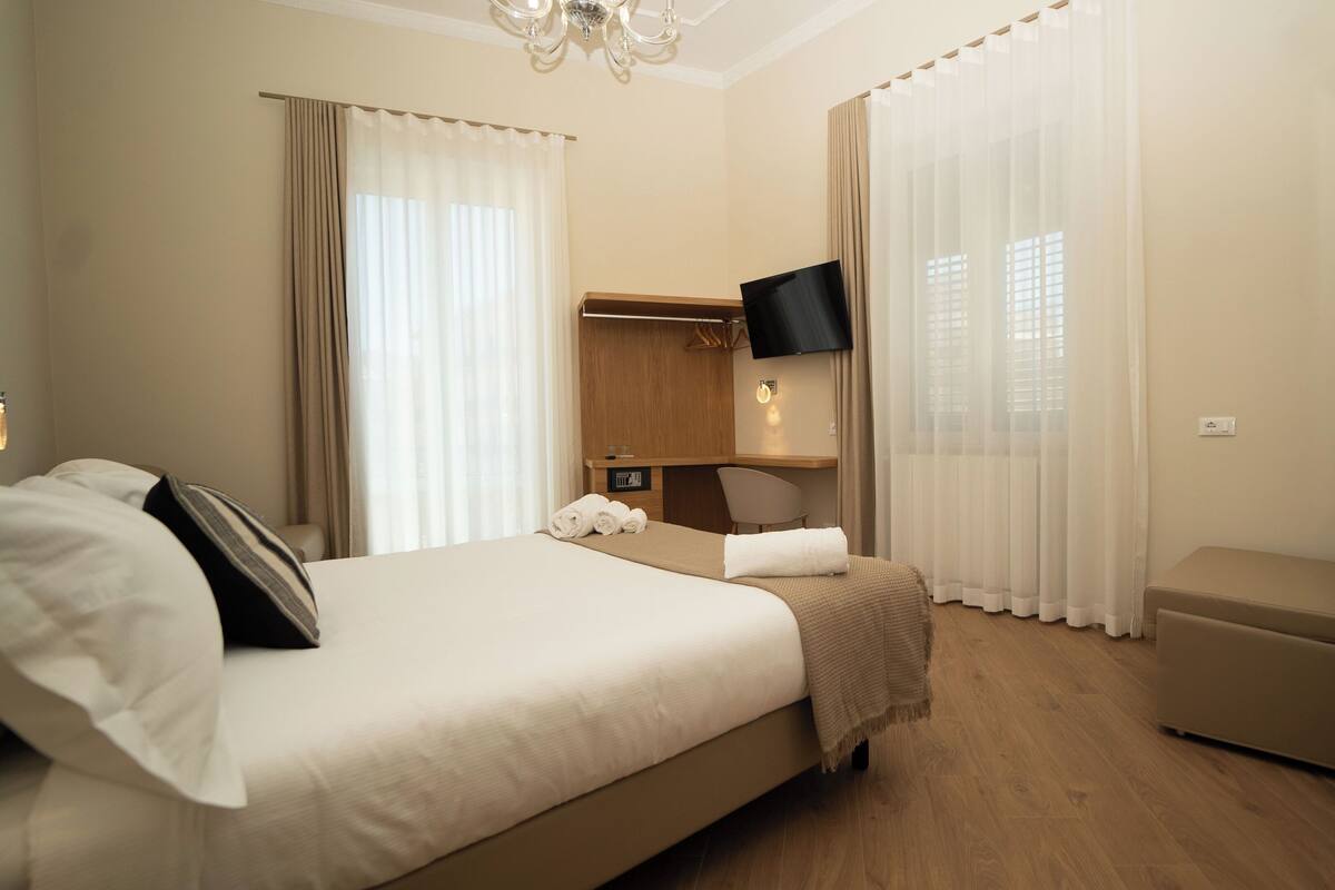 Una camera d'albergo con un letto grande, una scrivania, una sedia e una televisione.