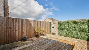 A wooden deck, a wooden fence, a green hedge, and a gate. - Host & Stay | Hithe House (Amble)