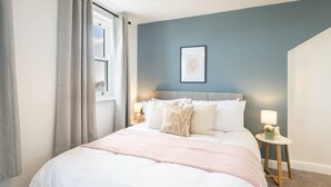 A bedroom with a bed, a nightstand, a framed picture on the wall, and a window with curtains. - Host & Stay | Hithe House (Amble)