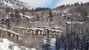 Une station de montagne enneigée, composée de plusieurs bâtiments de style chalet, chacun doté de balcons et d’une architecture rustique.