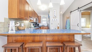 Une cuisine avec des meubles en bois, un îlot central recouvert de carreaux bleus et des tabourets de bar.