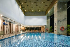 An indoor swimming pool with a tiled floor, a wooden ceiling, and a marble wall. - Wyndham Garden Legend Halong (Bai Chay)