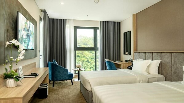A hotel room with two beds, a desk, a chair, a small table with a vase, and a large window with curtains. - Wyndham Garden Legend Halong (Bai Chay)