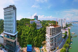 A high-rise building with multiple floors, surrounded by greenery and a river.