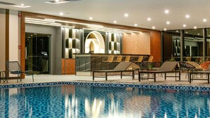 A poolside area with lounge chairs, a reception desk, and a modern interior design. - Wyndham Garden Legend Halong (Bai Chay)