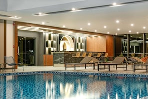 Un espace aménagé au bord de la piscine, avec des chaises longues, un comptoir d’accueil et un design intérieur moderne.