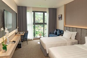 Une chambre d’hôtel avec deux lits, un bureau, une chaise, une petite table et une grande fenêtre avec des rideaux.
