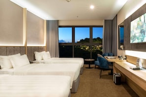 Une chambre d’hôtel avec deux lits, un bureau, une chaise, une télévision et une grande fenêtre donnant sur un beau paysage.