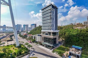 A modern high-rise building with multiple floors, surrounded by greenery and a clear sky. - Wyndham Garden Legend Halong (Bai Chay)