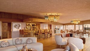 A spacious living area with a bar, multiple seating arrangements, and decorative lighting fixtures. - One Nature Mara River (Serengeti)