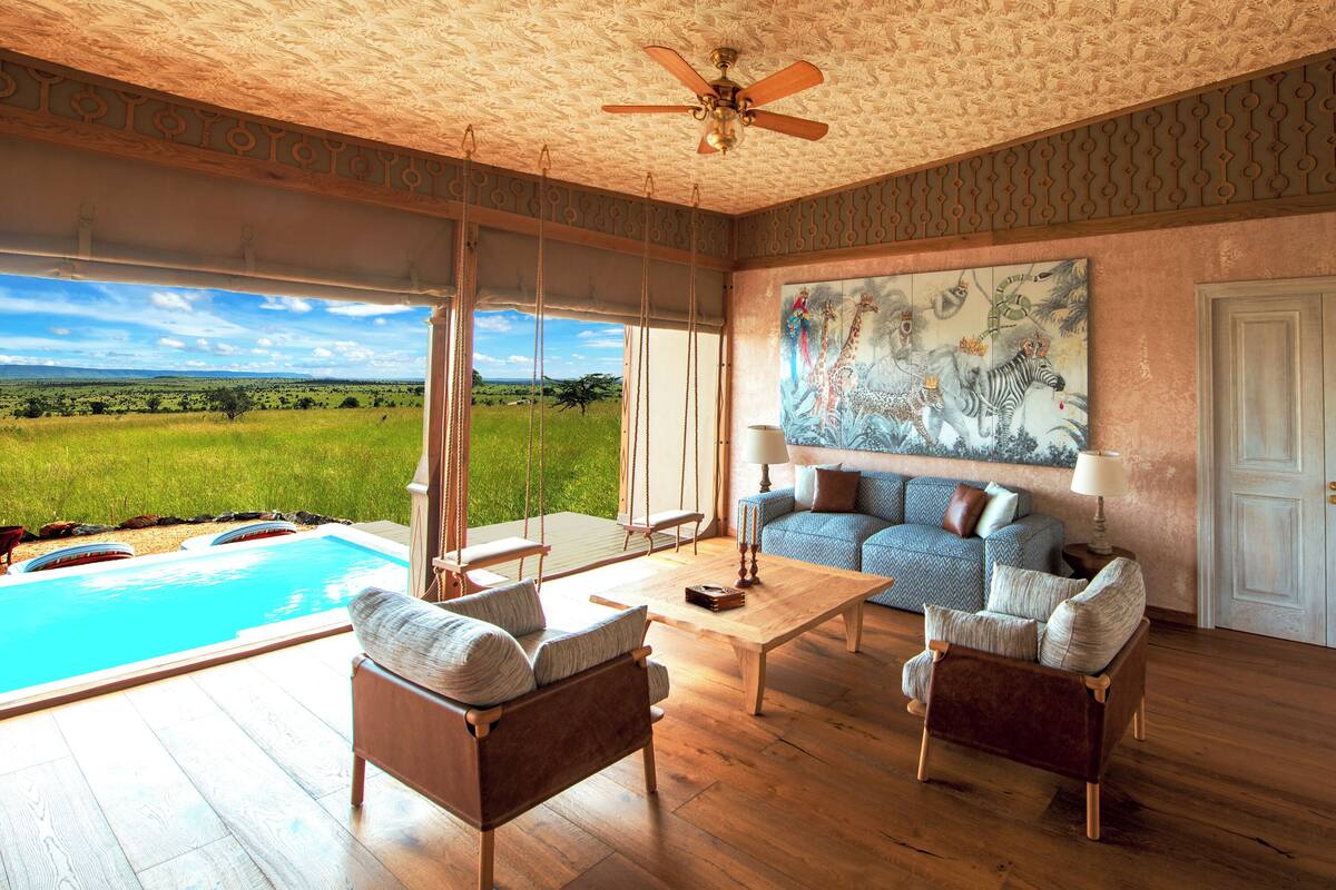 A spacious living room with a large painting, a pool, and a view of the outdoors.
