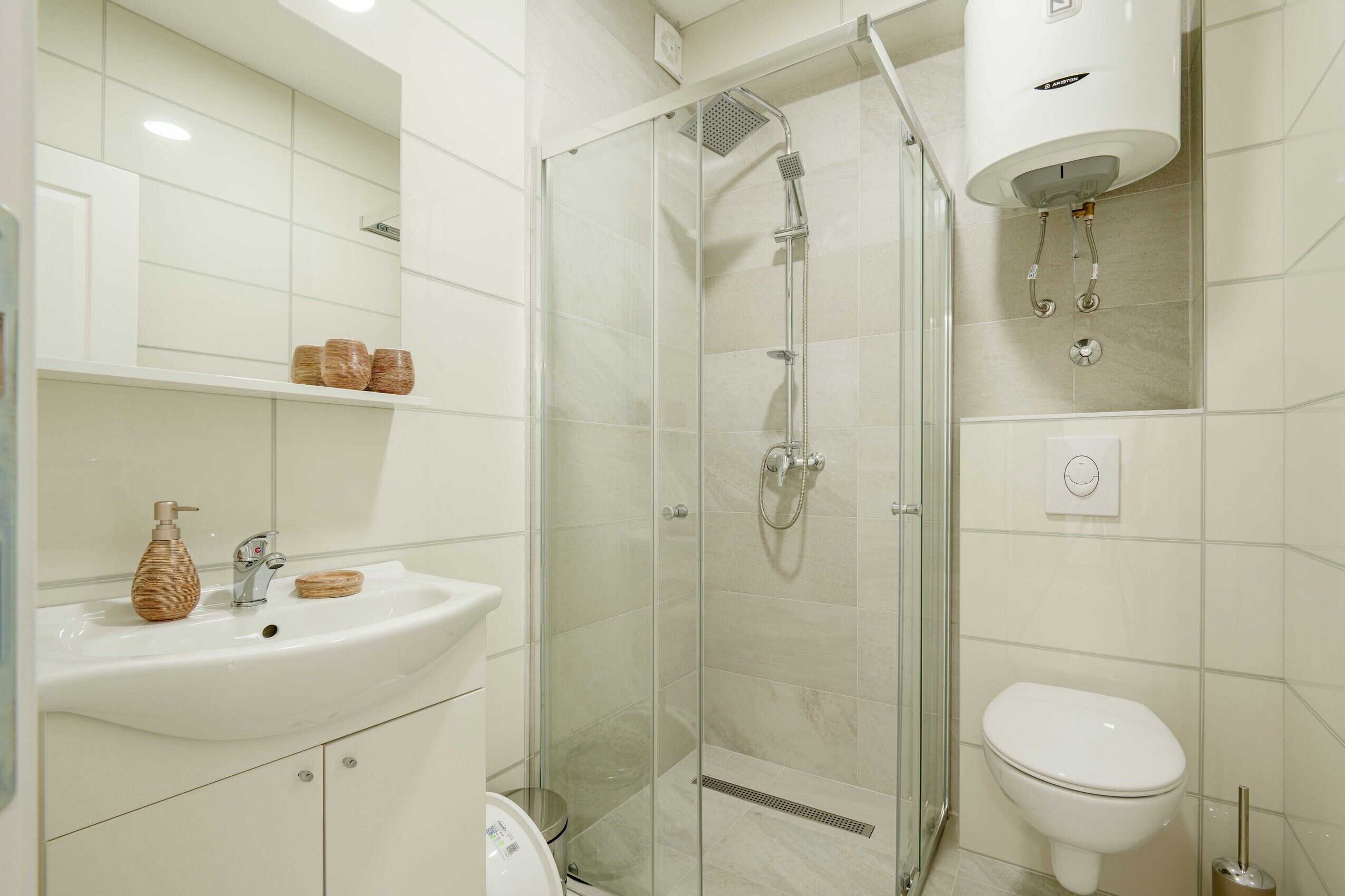 Un baño moderno con cabina de ducha de vidrio, un lavabo blanco y un inodoro.