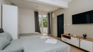 Une chambre d’hôtel moderne avec un grand lit, une télévision et un balcon doté de rideaux.