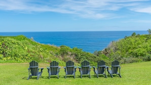 A grassy area with four Adirondack chairs facing a view of the ocean. - Kauai The Cliffs At Princeville 4209 1 Bedroom Condo (Princeville)