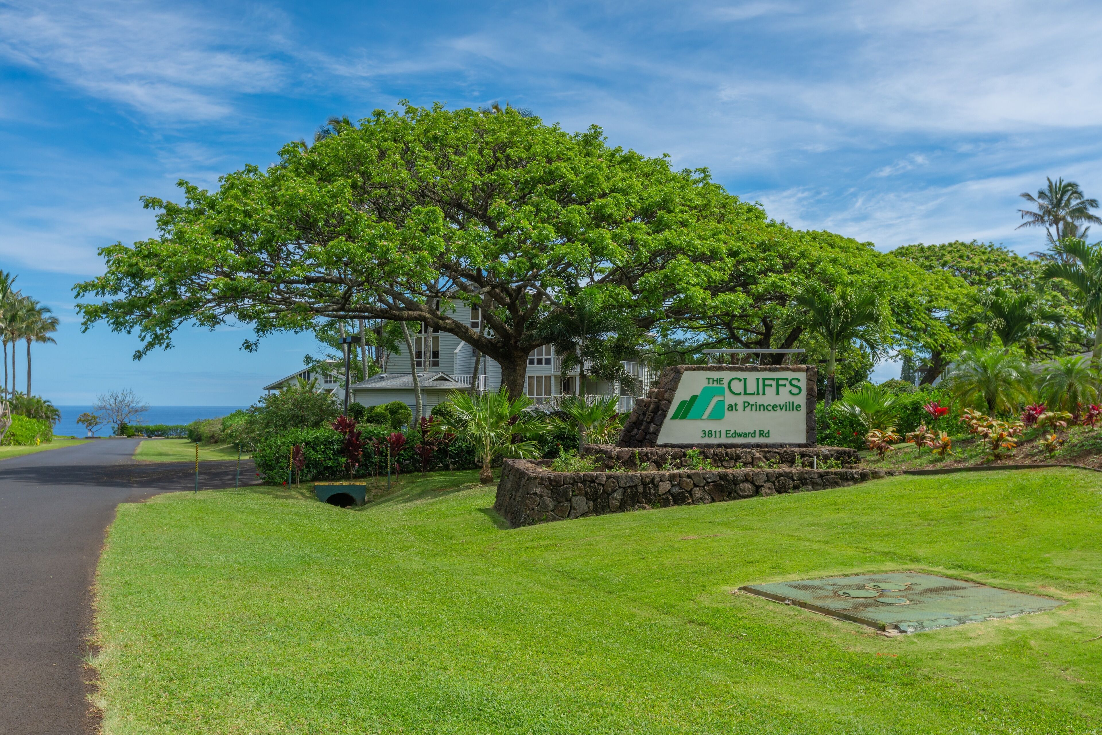 A large house with a sign reading "The Cliffs at Princeville" and a view of the ocean.
