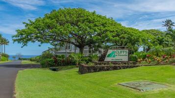 A large house with a sign reading "The Cliffs at Princeville" and a view of the ocean.