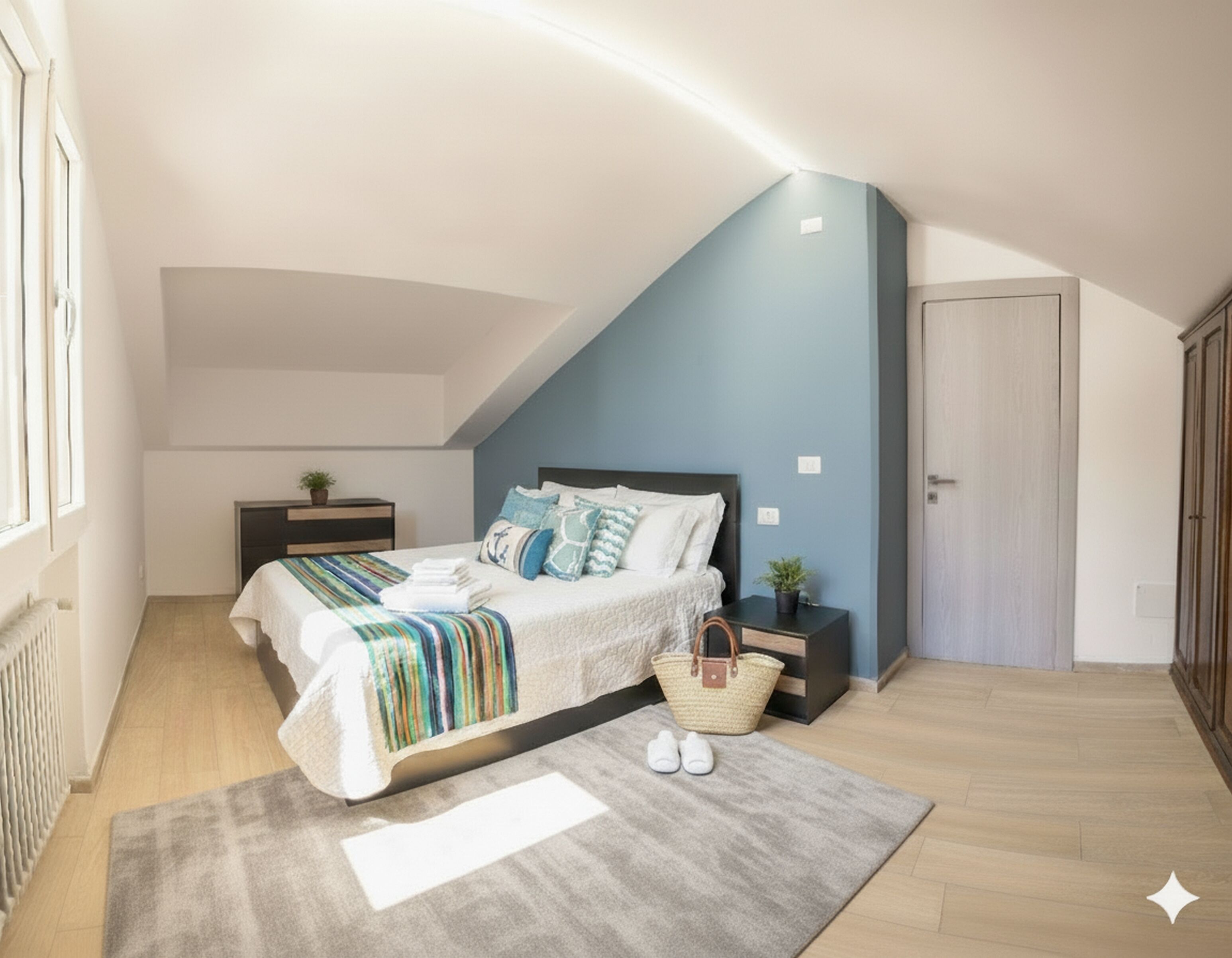 Quarto com teto inclinado, cama com manta listrada, mesa de cabeceira com planta e uma porta à direita.