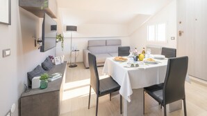 Un'area pranzo moderna con un tavolo rotondo, sedie e un divano sullo sfondo.