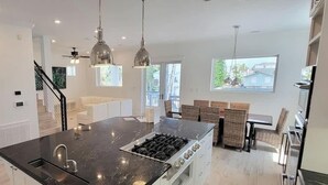 A modern kitchen with a central island, stainless steel appliances, and pendant lighting. - Padre Beach House 5 Bedroom Home by RedAwning (South Padre Island)