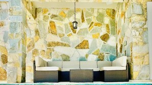 A stone-walled pool area with a seating arrangement. - Padre Beach House 5 Bedroom Home by RedAwning (South Padre Island)