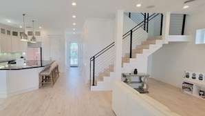 A modern kitchen with built-in appliances, a dining area, and a staircase leading to an upper level. - Padre Beach House 5 Bedroom Home by RedAwning (South Padre Island)