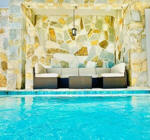 A stone-walled pool area with a seating arrangement. - Padre Beach House 5 Bedroom Home by RedAwning (South Padre Island)