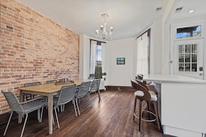 Un coin repas avec un mur en briques, une table en bois et des chaises en métal.