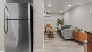 A compact kitchen with a stainless steel refrigerator, a wooden cabinet, and a dining area with a sofa and a small table.